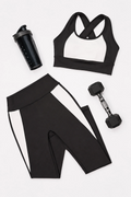 Black and white color block style sports bra, leggings, shaker bottle, and dumbbell on a white background