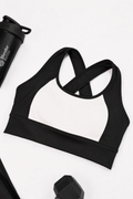 Black and white contrast sports bra on a white background with a blender bottle partially visible.