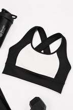 Black and white contrast sports bra on a white background with a blender bottle partially visible.